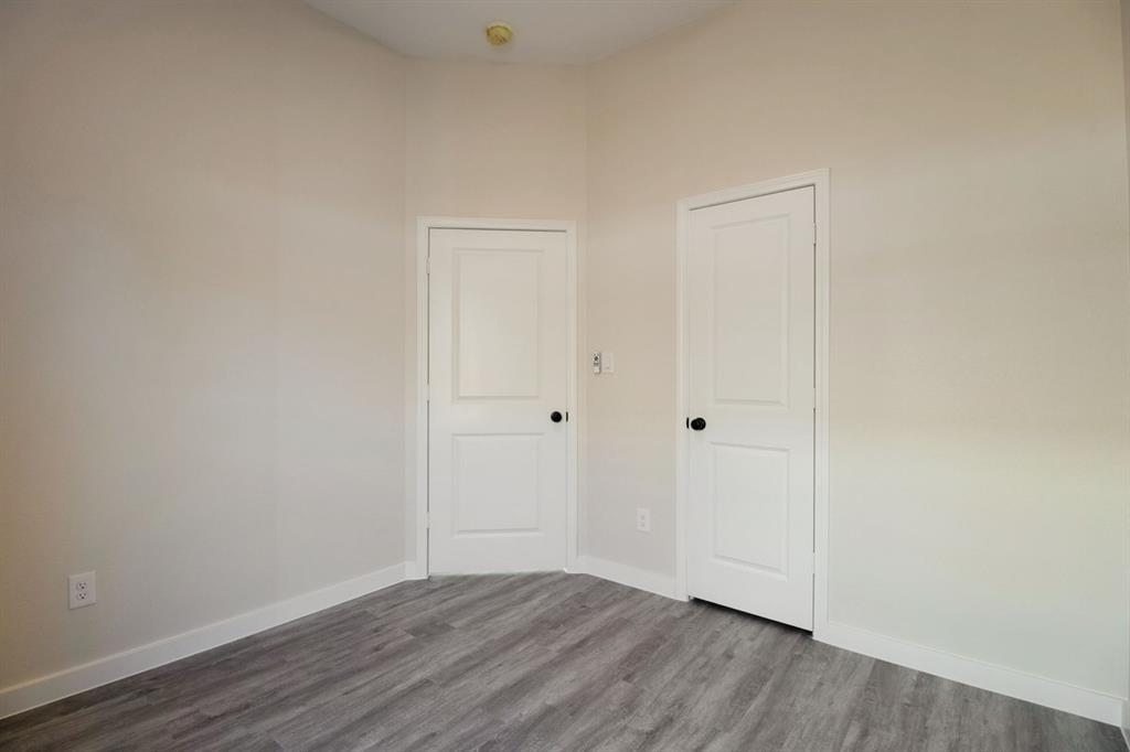 Light-toned walls, two panel doors with matte black hardware, and wood-finish flooring