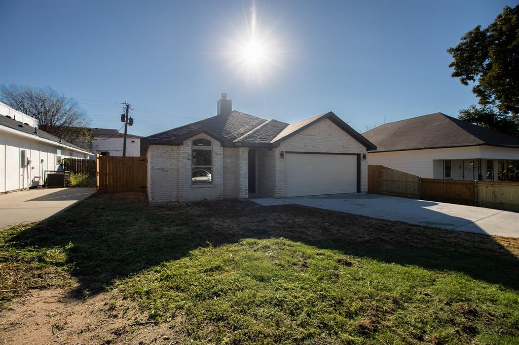 Light brick exterior, arched window, attached garage, concrete driveway, wood privacy fence