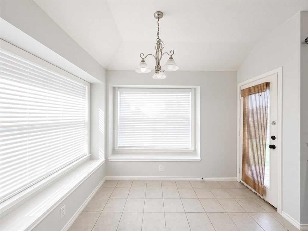 Interior space featuring tile flooring, dual bay windows with integrated sills, a multi-light brushed nickel chandelier, and a glass-paneled exterior door Interior space featuring tile flooring, dual bay windows with integrated sills, a multi-light brushed nickel chandelier, and a glass-paneled exterior door