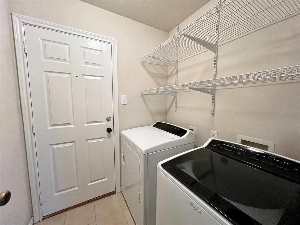 Utility space featuring white tile flooring, a six-panel door, and white wire wall-mounted shelving Utility space featuring white tile flooring, a six-panel door, and white wire wall-mounted shelving