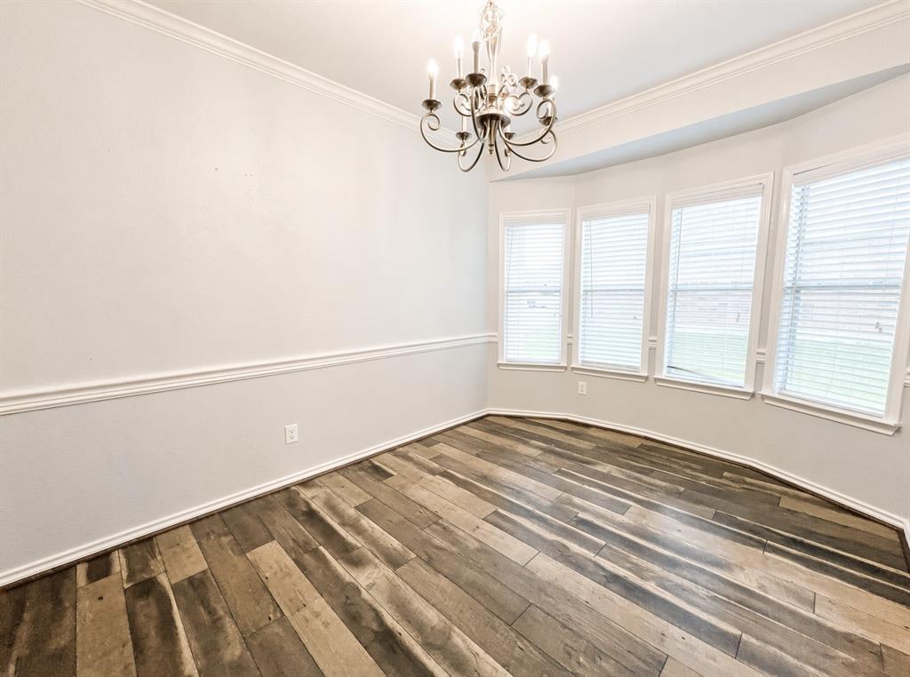 Wood-finish flooring, bay window, crown molding, chair rail, and decorative chandelier Wood-finish flooring, bay window, crown molding, chair rail, and decorative chandelier