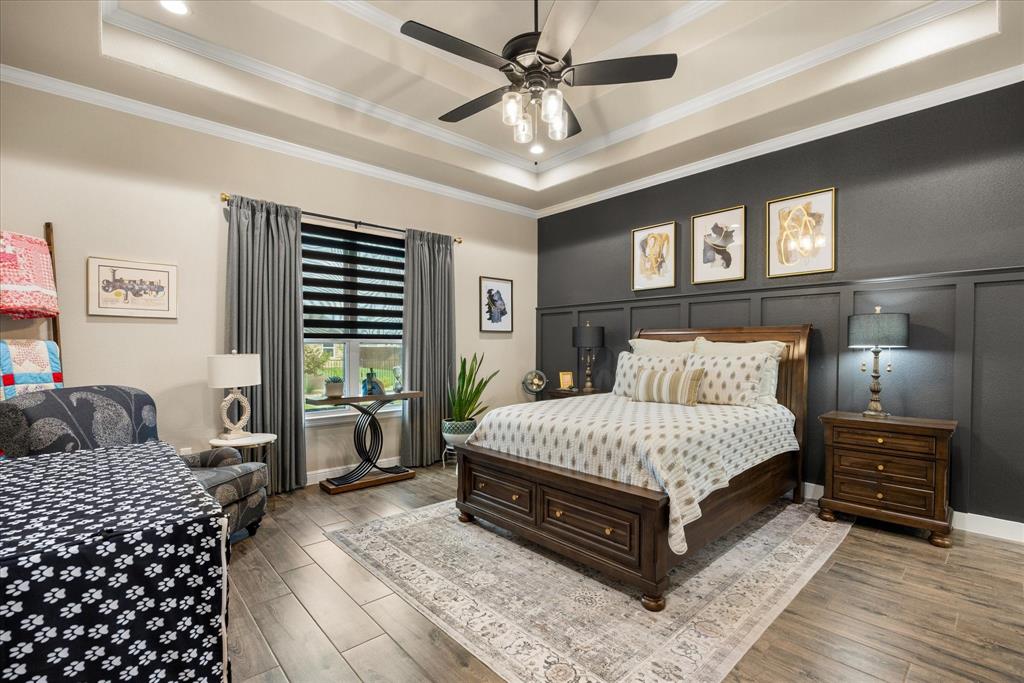 Tray ceiling with crown molding, wood-finish flooring, and decorative wall paneling