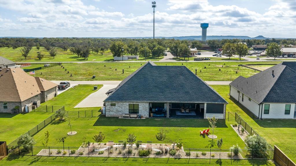 Rear exterior featuring a covered patio, metal perimeter fencing, a manicured lawn, and professional landscape beds
