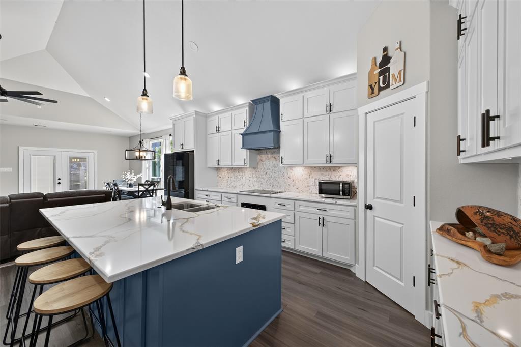 Beautifully designed kitchen featuring an oversized island with quartz countertops, custom cabinetry with plenty of storage, stainless steel appliances. Open to living and dining area.