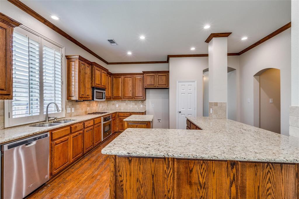 Kitchen featuring wood cabinetry, stone countertops, stainless steel dishwasher, wood-finish flooring, and recessed ceiling lighting