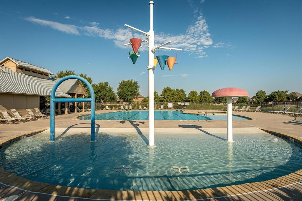Zero-depth entry splash pad featuring a water feature with dumping buckets and a mushroom-shaped water fountain, accompanied by a full-size lap pool and concrete pool deck