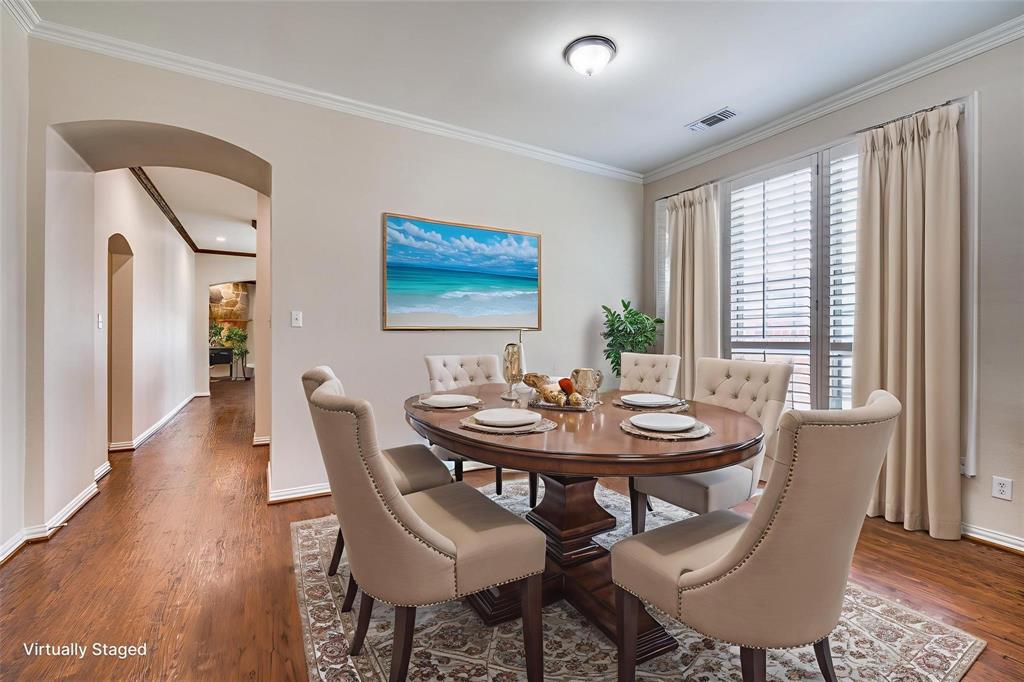 Dining area featuring wood-finish flooring, crown molding, arched entryways, and floor-to-ceiling windows with horizontal blinds