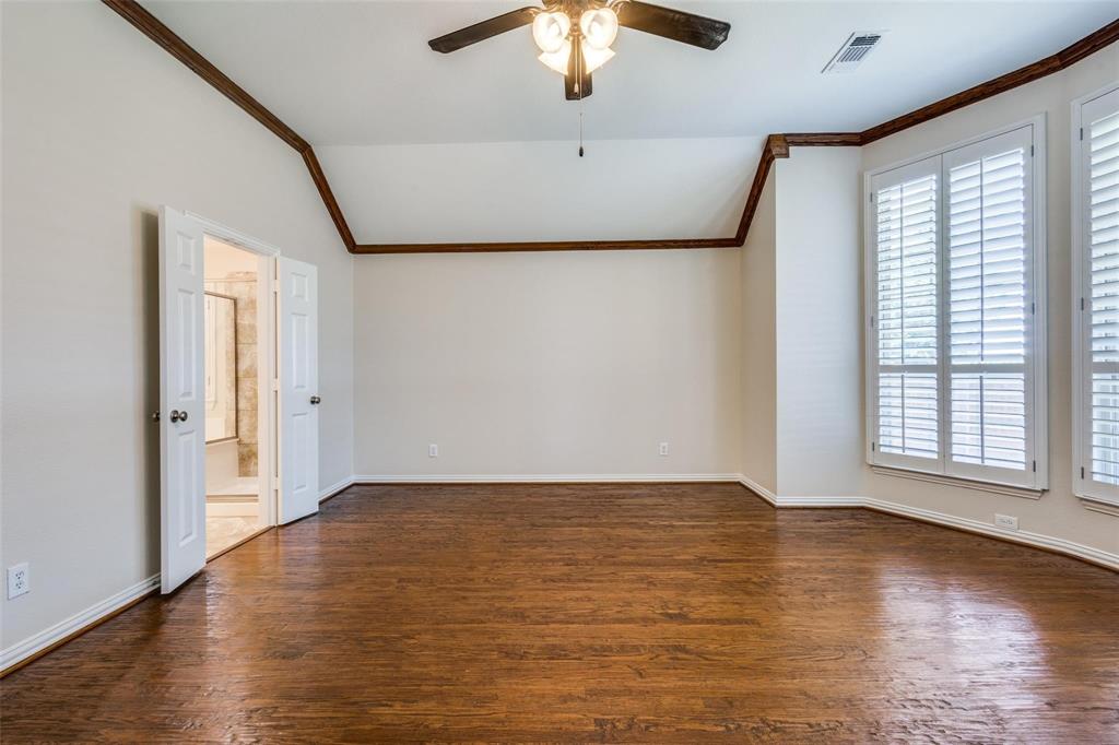 Vaulted ceiling with crown molding, wood-finish flooring, plantation shutters, and a ceiling-mounted light fixture with a fan