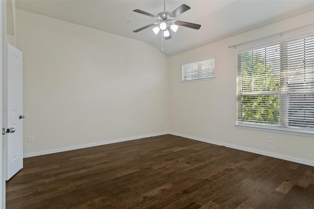 Vaulted ceiling with a central multi-light ceiling fan, wood-finish flooring, and multi-pane windows with horizontal blinds