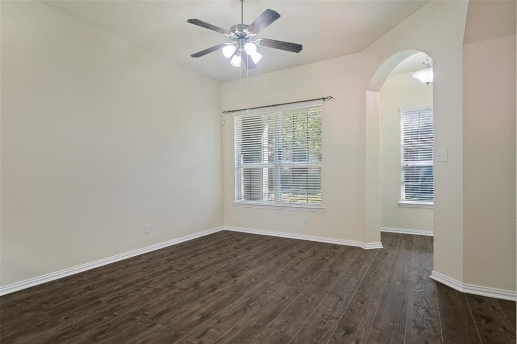 Room featuring wood-finish flooring, an arched entryway, neutral wall tones, a ceiling fan with integrated lighting, and horizontal window blinds