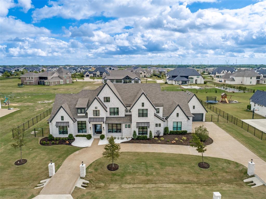 Multi-gabled exterior featuring light brick masonry, metal roof accents, multi-pane windows, a sprawling front lawn, and a wide concrete circular driveway Multi-gabled exterior featuring light brick masonry, metal roof accents, multi-pane windows, a sprawling front lawn, and a wide concrete circular driveway