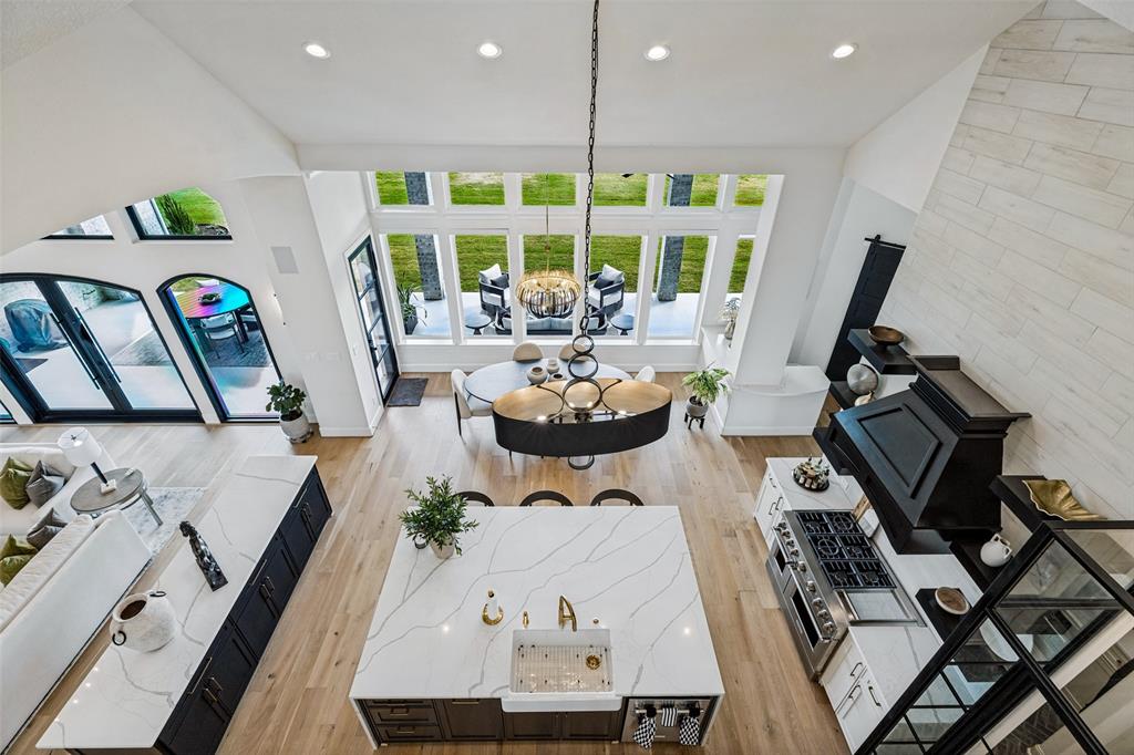 Vaulted ceilings, expansive windows, large center island with integrated apron-front sink, stone-finish kitchen hood, and light-tone wood-finish flooring