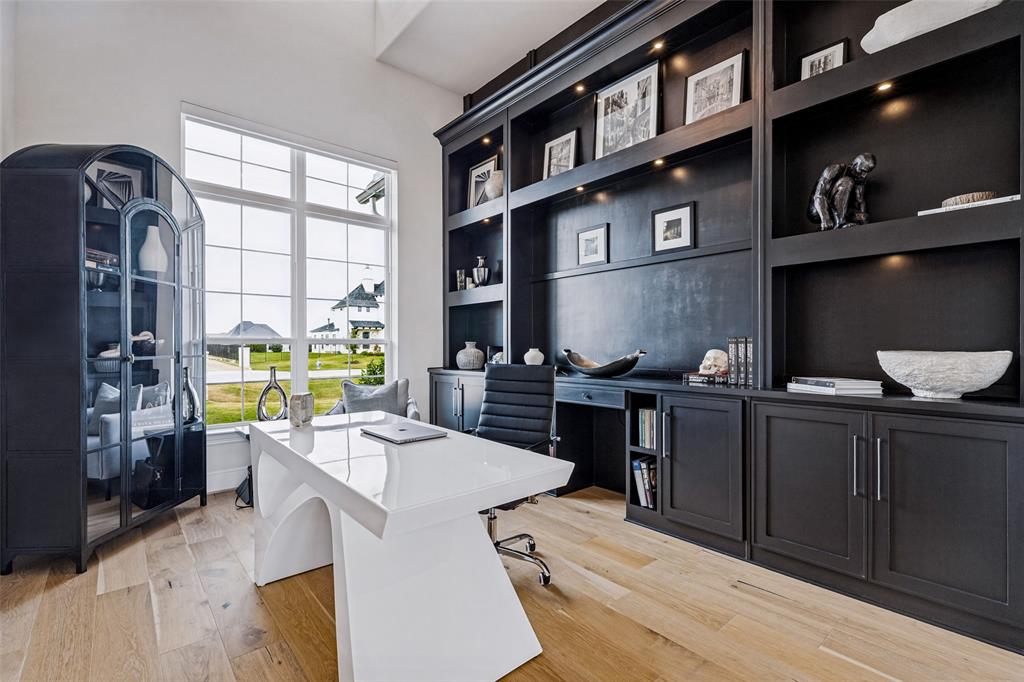 Floor-to-ceiling custom cabinetry with integrated display lighting, wood-finish flooring, and expansive grid-patterned windows Floor-to-ceiling custom cabinetry with integrated display lighting, wood-finish flooring, and expansive grid-patterned windows