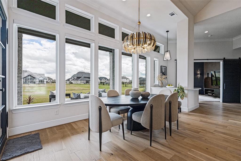 Floor-to-ceiling windows, wood-finish flooring, custom statement chandelier, high ceilings, and sliding barn-style door
