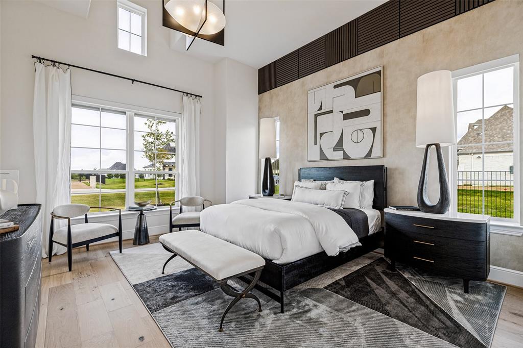 High-ceiling room featuring wood-finish flooring, multi-pane windows, a geometric accent wall treatment, and a modern tiered chandelier