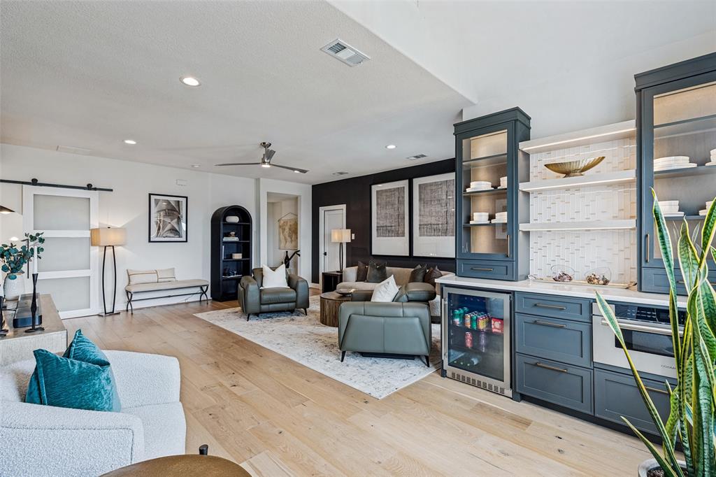 Open concept living space featuring wood-finish flooring, recessed lighting, and custom cabinetry with integrated glass-front display towers