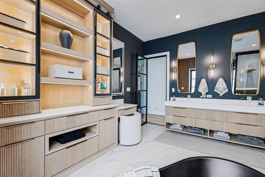Custom light-wood cabinetry featuring vertical reeding, integrated interior lighting, and black metal-framed glass shelving
