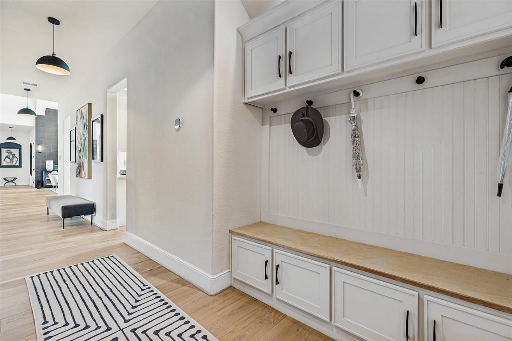 Built-in white cabinetry featuring beadboard paneling, upper storage lockers, lower base cabinets, a wood-finish bench seat, and matte black hardware