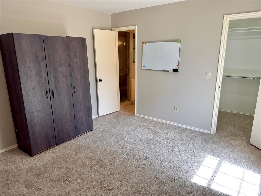 Neutral wall palette, carpeting, and walk-in closet featuring shelving and hanging rods
