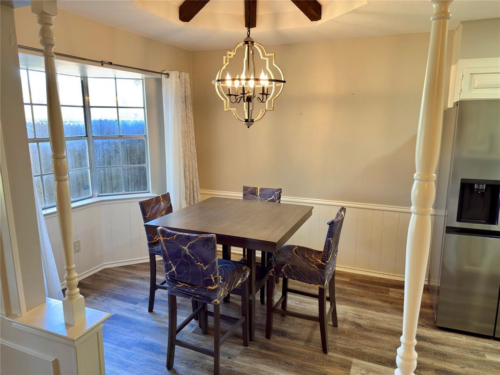 Bay window featuring multi-pane glass, wood-finish flooring, wainscoting, and a geometric metal pendant light fixture Bay window featuring multi-pane glass, wood-finish flooring, wainscoting, and a geometric metal pendant light fixture