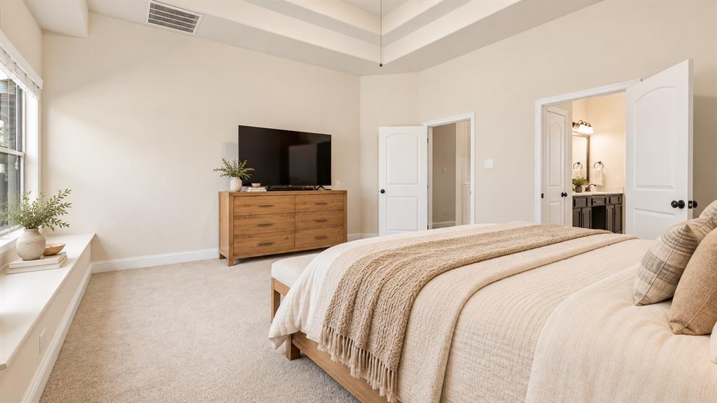Bedroom featuring a tray ceiling, plush carpeting, built-in window seat, and dual-panel interior doors