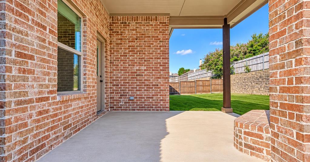 Covered concrete patio featuring brick exterior walls, a built-in brick sitting wall, and supporting structural columns