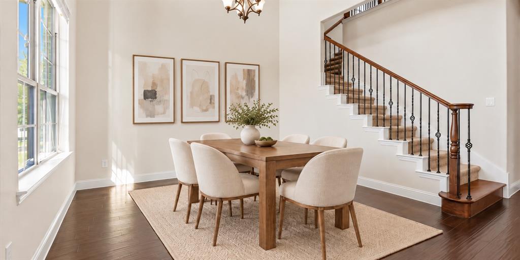 Double-height ceilings, wood-finish flooring, staircase with dark wood handrail and metal balusters, and multi-pane windows