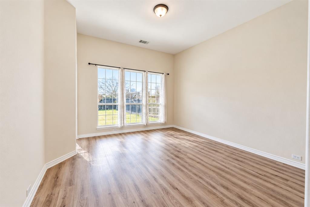 Family room featuring wood-look LVP flooring, a triple-pane window arrangement, neutral wall paint, and a ceiling-mounted light fixture Family room featuring wood-look LVP flooring, a triple-pane window arrangement, neutral wall paint, and a ceiling-mounted light fixture