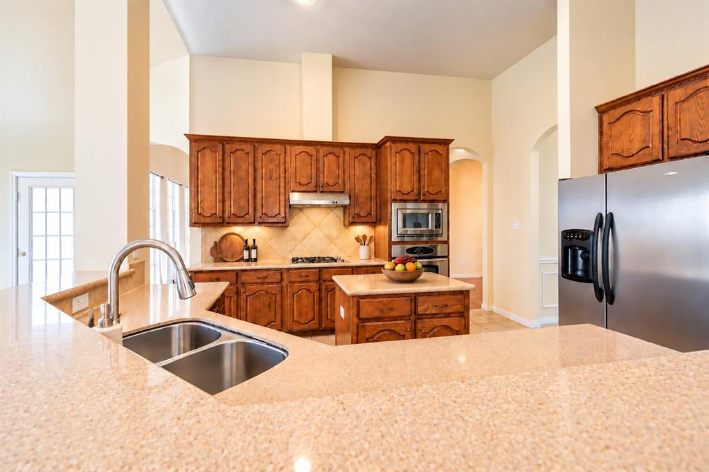 Kitchen featuring wood cabinetry, granite countertops, stainless steel appliances, a center island, and a double-basin undermount sink *Virtually staged to show potential* Kitchen featuring wood cabinetry, granite countertops, stainless steel appliances, a center island, and a double-basin undermount sink *Virtually staged to show potential*
