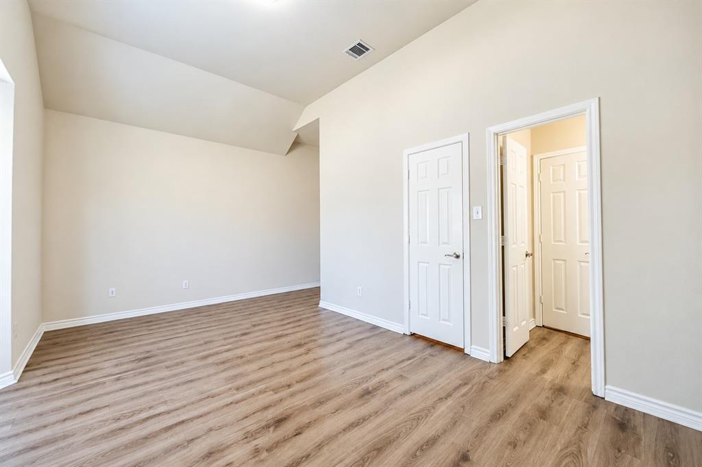 Vaulted ceilings, wood-look LVP flooring, and neutral wall tones