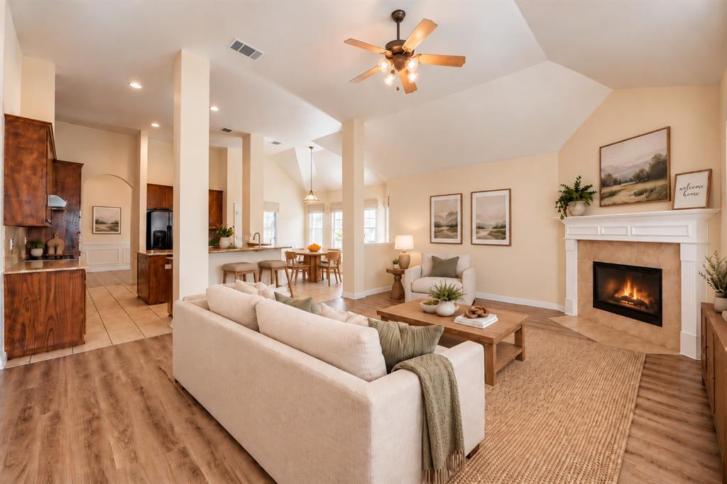 Vaulted ceilings, fireplace with custom mantle, wood-look LVP flooring, recessed lighting, and kitchen with cabinetry and counter seating   *Virtually staged to show potential*