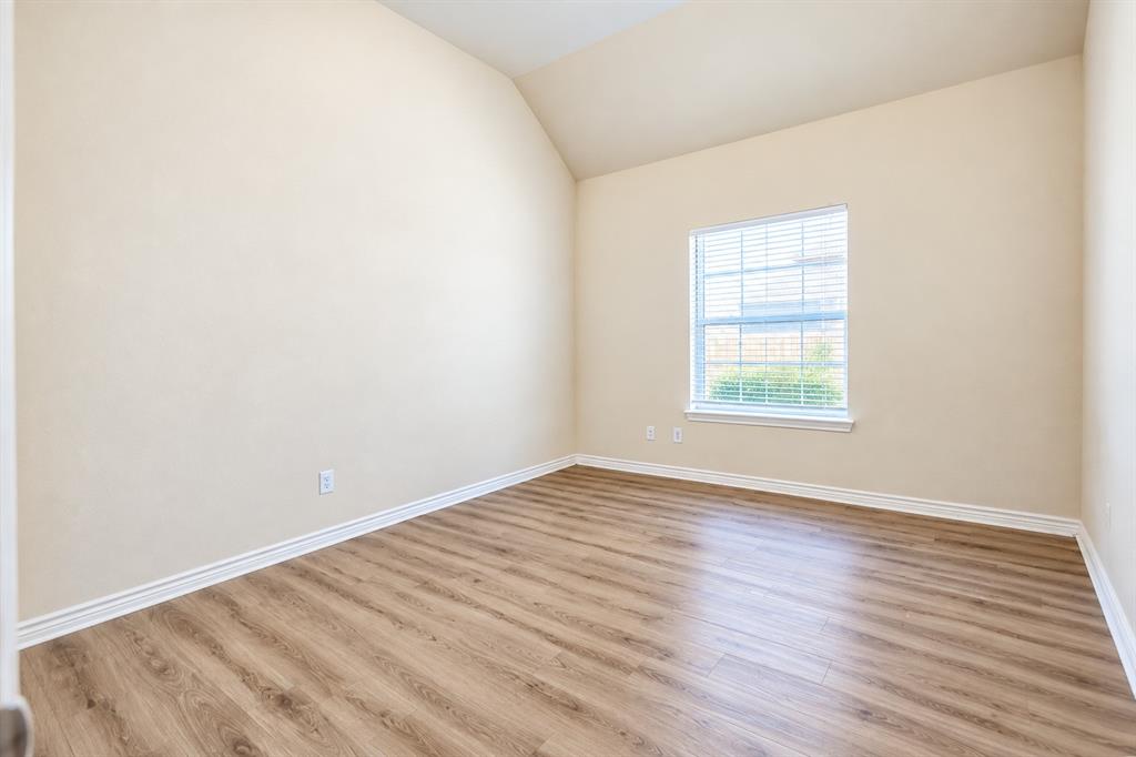 Vaulted ceilings, wood-look LVP flooring, and a single-pane window with installed blinds