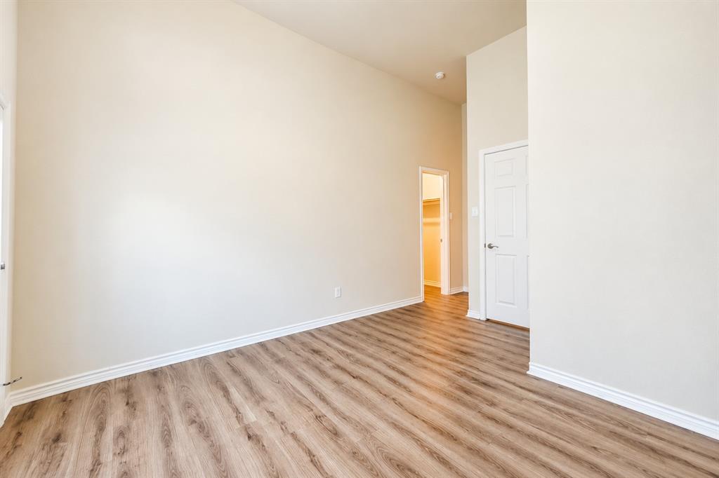 High ceilings with neutral wall paint, wood-look LVP flooring, six-panel interior doors, and a built-in closet