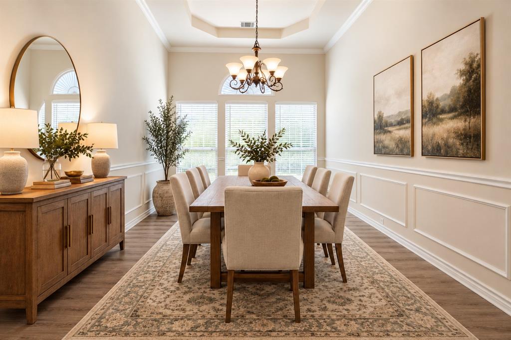 Dining space featuring a tray ceiling, wainscoting, wood-finish flooring, multi-pane windows with arched transoms, and a chandelier. *Virtually staged to show potential* Dining space featuring a tray ceiling, wainscoting, wood-finish flooring, multi-pane windows with arched transoms, and a chandelier. *Virtually staged to show potential*