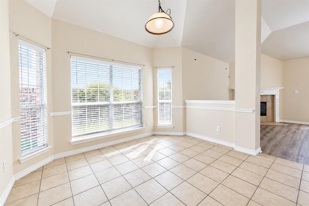 Vaulted ceilings, large windows with horizontal blinds, neutral tile flooring, chair rail molding, and a dome-style pendant light fixture Vaulted ceilings, large windows with horizontal blinds, neutral tile flooring, chair rail molding, and a dome-style pendant light fixture