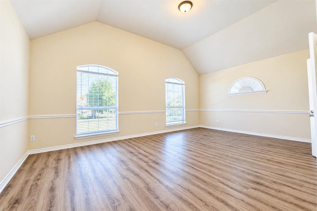 Vaulted ceilings, wood-look LVP flooring, chair rail molding, and arched windows with integrated blinds
