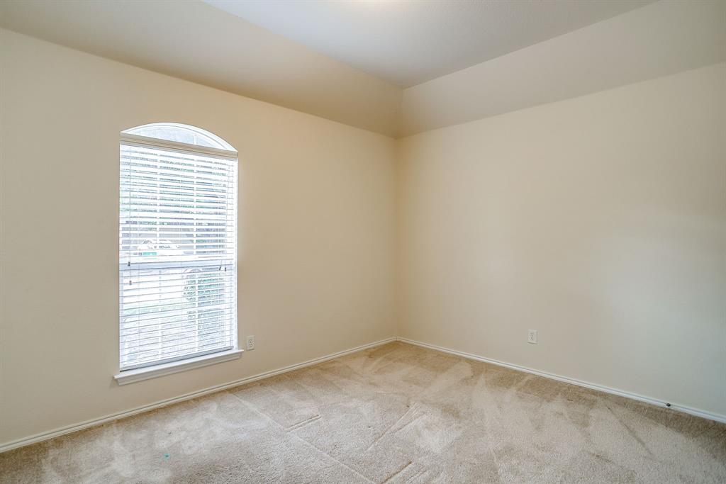 Room with vaulted ceiling, neutral wall tones, wall-to-wall carpeting, and an arched window featuring horizontal blinds