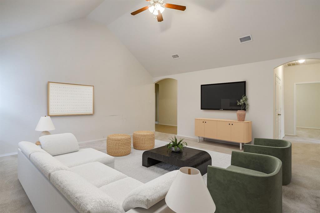 Living area featuring vaulted ceilings, arched room entries, and a ceiling fan with integrated lighting