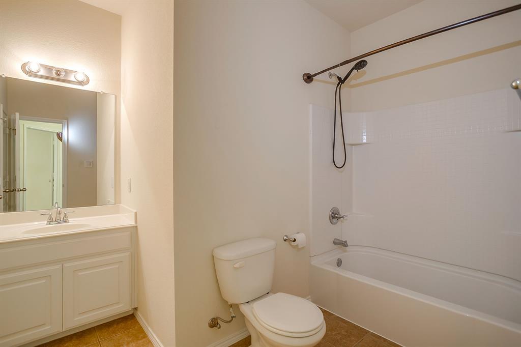 Bathroom featuring a white vanity with a integrated countertop basin, wall-mounted mirror, three-light vanity fixture, and a tub-shower combination with a hand-held showerhead