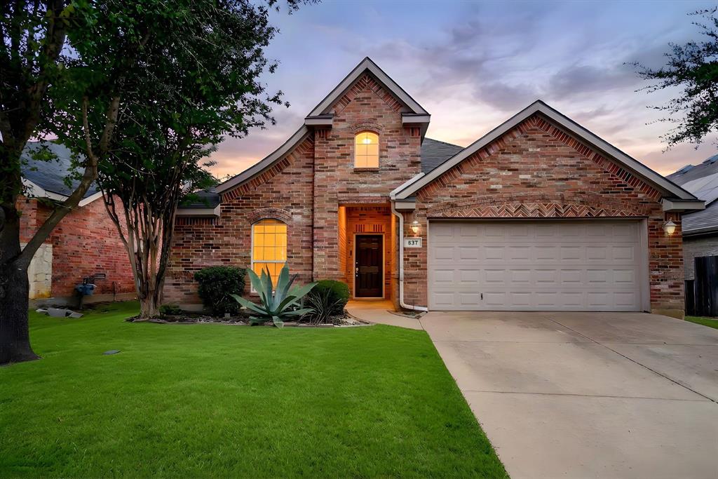 Brick exterior featuring a multi-gabled roofline, decorative masonry accents, an arched window, and an attached two-car garage