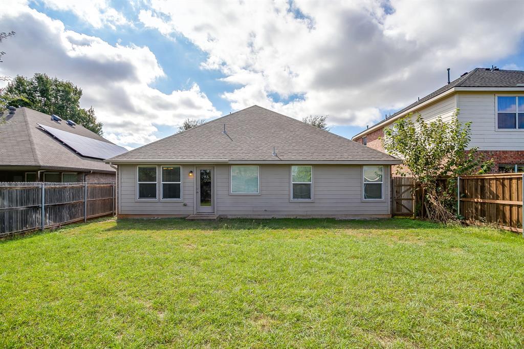 Rear exterior featuring horizontal lap siding, a hip roof, multi-pane windows, and a fenced backyard