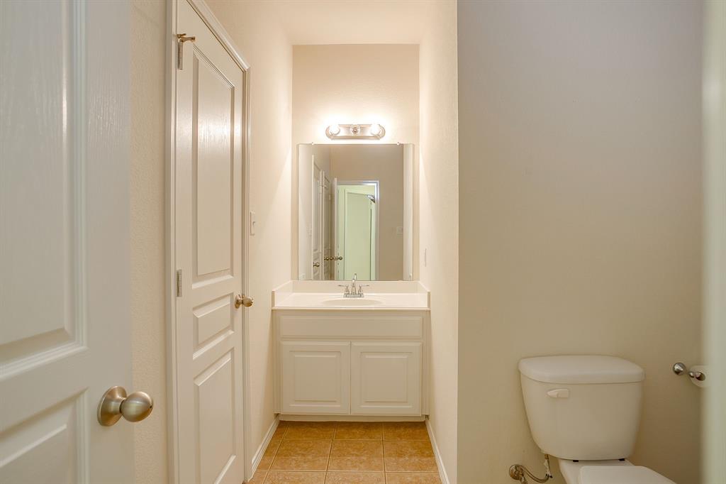 White vanity cabinet featuring a solid-surface countertop with an integrated basin, wall-mounted mirror, two-light fixture, and ceramic tile flooring