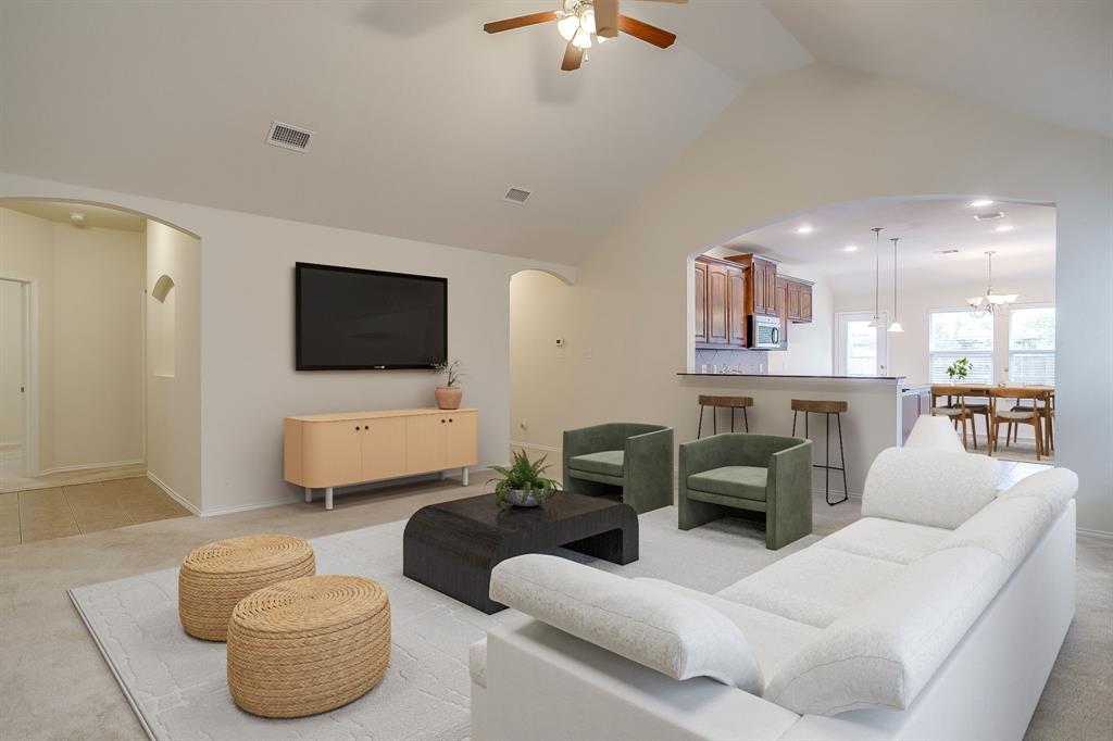 Vaulted ceilings, arched wall openings, neutral carpeting, and a built-in breakfast bar
