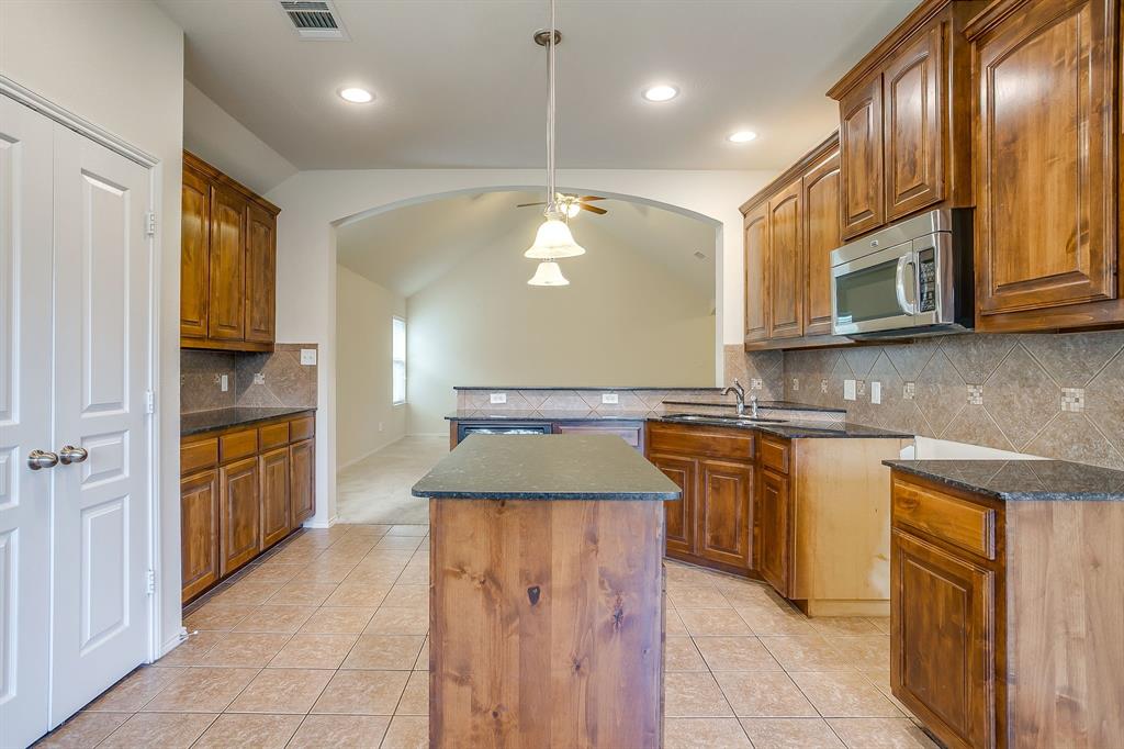 Kitchen featuring stained wood cabinetry, central island, stone-finish countertops, tile backsplash, and recessed lighting