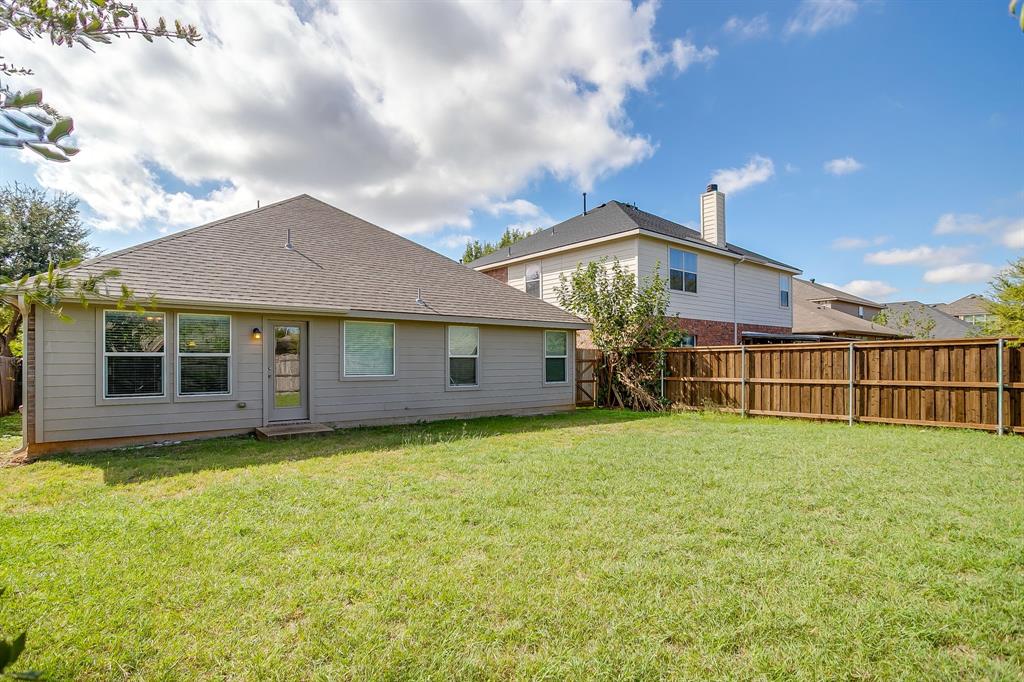 Exterior rear elevation featuring horizontal siding, a hipped roofline, and a fenced backyard
