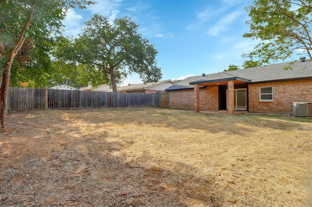 Backyard featuring brick exterior walls, a covered patio with brick support columns, and full wood privacy fencing
