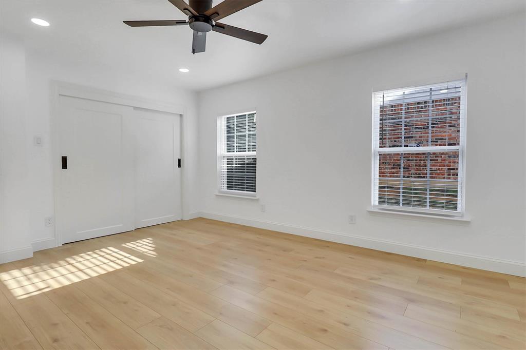 Interior room featuring wood-finish flooring, recessed lighting, a ceiling fan, sliding closet doors, and dual windows
