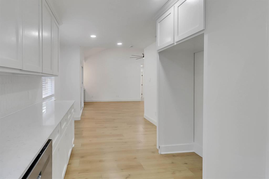 White Shaker-style cabinetry, solid-surface countertops, recessed ceiling lighting, and wood-finish flooring