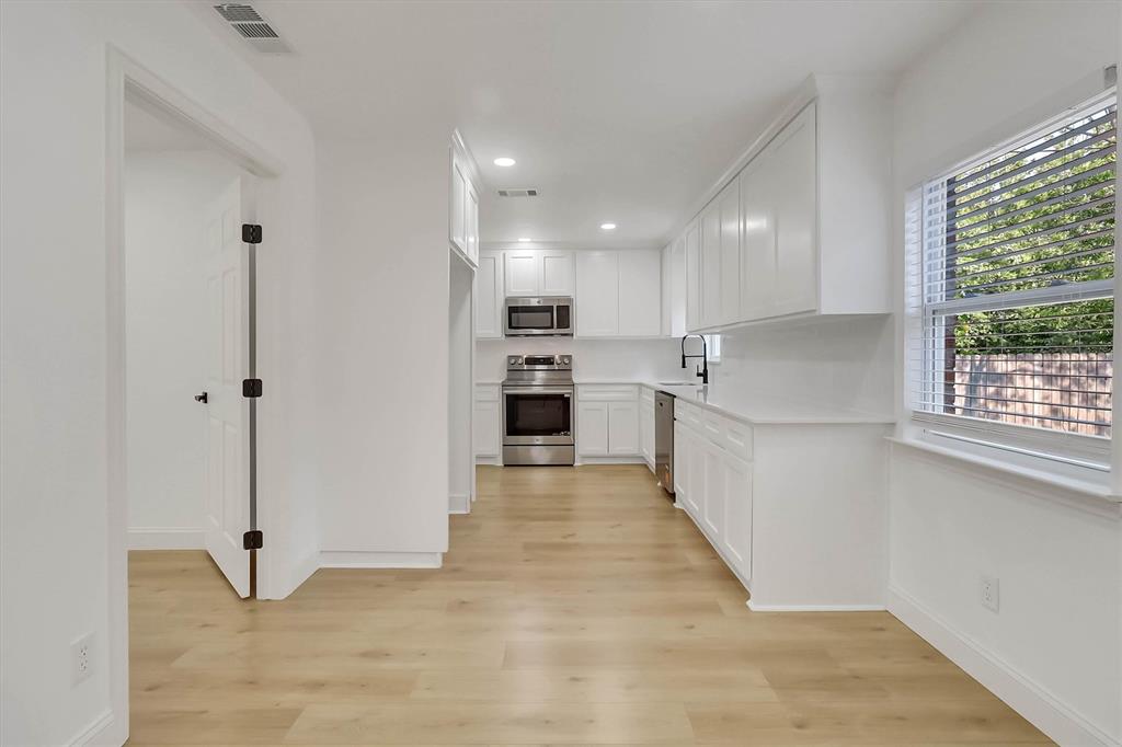 Kitchen featuring white shaker cabinetry, stainless steel appliances, light wood-finish flooring, quartz countertops, and a matte black faucet