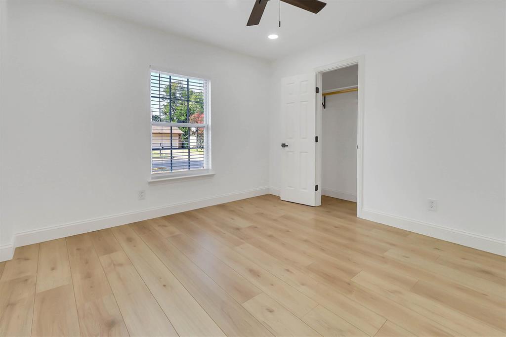 Neutral-toned wood-finish flooring, recessed lighting, ceiling fan, single-hung window, and a reach-in closet with built-in rod